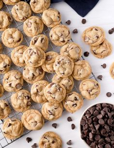 cookies and chocolate chips on a cooling rack next to a bowl of chocolate chip cookies