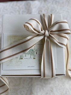 an open gift box with a ribbon tied around it on top of a white blanket