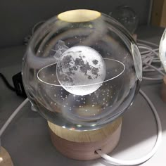 a glass ball with an image of the moon inside it on a table next to a charger