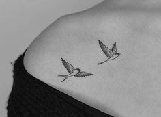 two small birds flying in the air on top of a woman's back shoulder