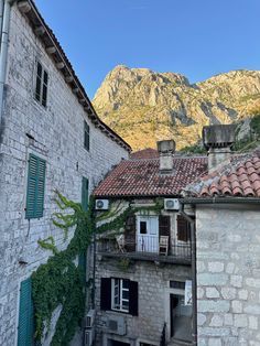 an old stone building with ivy growing on it's side and mountains in the background