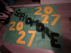 a green and yellow sign with numbers written in black on the bottom right hand corner