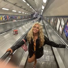 a woman is standing on an escalator with her arms spread out and smiling