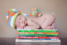 a baby laying on top of a stack of books wearing a knitted hat and diaper