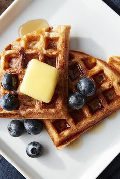 two waffles with blueberries and butter on top are sitting on a plate