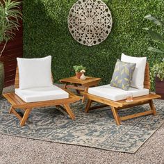 two wooden lounge chairs sitting next to each other in front of a wall covered with greenery