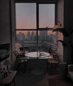 a living room filled with furniture and a large window overlooking a cityscape in the distance