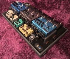 four different pedals sitting on top of a black case with purple furnishing