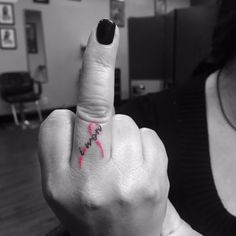 a woman pointing her finger at the camera with a pink tattoo on her left hand