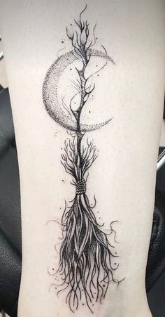 a woman's back with a tree and moon tattoo on her lower leg, which is