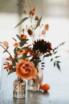 two vases with flowers in them sitting on a table