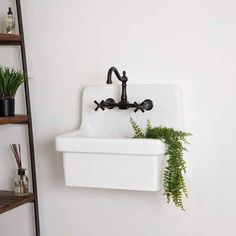 a white sink sitting under a faucet next to a shelf filled with plants