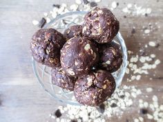 a glass bowl filled with chocolate and oatmeal balls on top of a wooden table