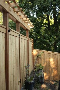 a wooden fence with potted plants in the foreground and trees in the background