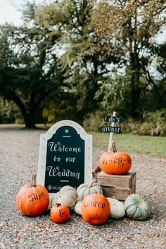 pumpkins sitting on the ground in front of a sign that says welcome to our wedding