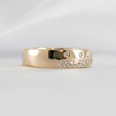 a gold wedding ring with diamonds on it's side, sitting on a white surface