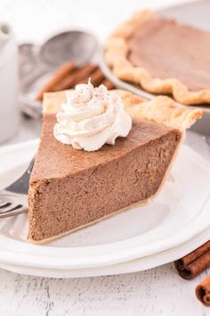 a slice of chocolate pie with whipped cream on top and cinnamon sticks next to it