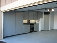 an open garage door shows the kitchen and living room in this apartment with gray cabinets