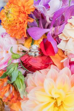 the wedding rings are on top of colorful flowers