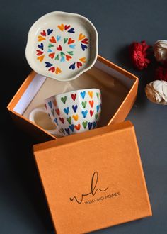 two cups in a box with the lid open next to some dried flowers on a table