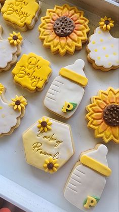 decorated cookies in the shape of sunflowers and baby bottles are on a tray