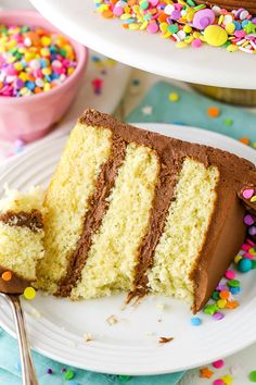 a slice of cake on a plate with sprinkles next to the cake