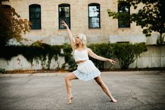 a woman in a white dress is playing with a frisbee on the street