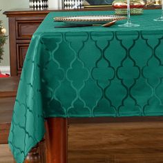 a table with a green table cloth and two wine glasses sitting on top of it