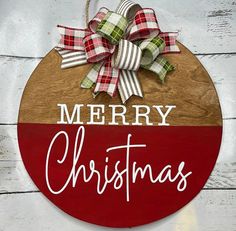 a merry christmas sign hanging on the side of a wooden wall with plaid ribbon and bow