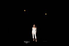 a woman is standing in the dark with stars above her head and she has one hand on her hips