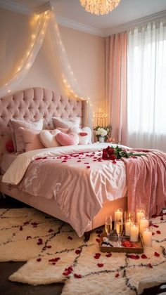 a bedroom decorated in pink and white with roses on the bed, chandelier and candles