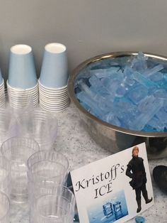 there are cups and bowls on the table with ice cubes next to each other