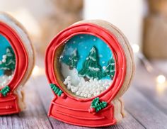 two snow globes sitting on top of a wooden table next to each other with christmas trees in them