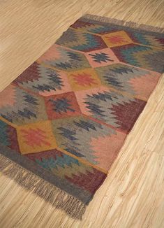 a multicolored area rug with fringes on top of wood floor next to wooden flooring