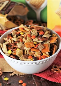 a white bowl filled with cheetos and candy corn snack mix on top of a red towel