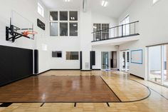 an indoor basketball court with hardwood floors and glass doors on the second floor is shown