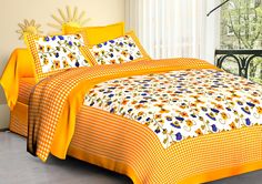 an orange and white comforter set with flowers on the bedspread in front of a window