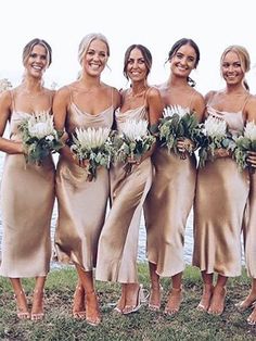 a group of women standing next to each other on top of a grass covered field