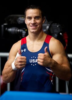 a man giving the thumbs up while standing in front of a camera and holding his thumb up