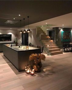 a large kitchen with candles on the counter and stairs leading up to an open floor plan