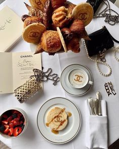 a table topped with desserts and pastries on top of white cloth covered plates