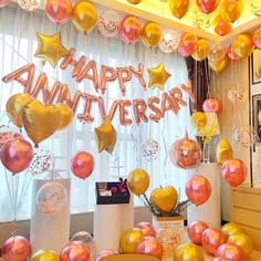 balloons and streamers are on display in front of a window with the words happy anniversary