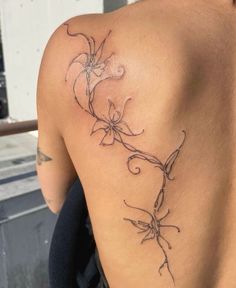 the back of a woman's shoulder with flowers on it and vines in the middle