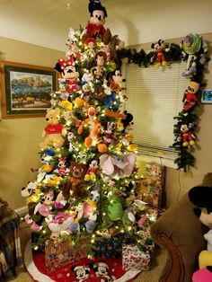 a christmas tree decorated with mickey mouses and other disney characters is in the living room