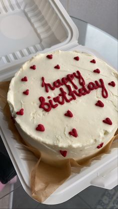 a birthday cake with white frosting and red sprinkles in a plastic container