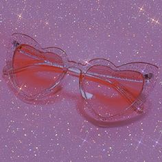 a pair of pink heart shaped glasses on a purple background with stars and sparkles