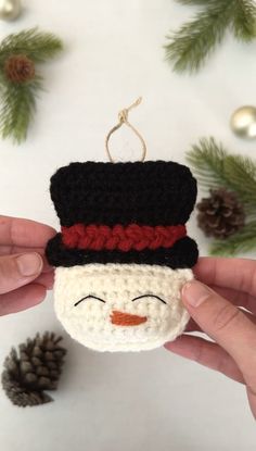 someone is holding a crocheted ornament with a snowman face on it