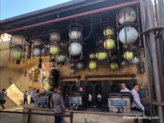 some people are standing around an old machine with lots of balls on the top and sides