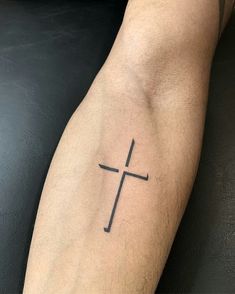 a man's arm with a small cross tattoo on the left side of his arm