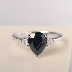 All HANDMADE ITEMS SHIP IN APPROX 8 DAYS Main Stone: Genuine natural black spinel Main Stone Size: Pear cut 7 mm x 9 mm Main Stone Weight: 2.23 carat Side Stone: Trillion cut CZ Height From The Ring Setting Bottom(to gemstone top): about 5.88 mm Width of Ring band Measure: gradually varied,about 1.28 to 2.03 mm Material: 925 Sterling Silver/14K White Gold/14K Yellow Gold/14k Rose Gold Engraved: Available For FreeNo more than 13 letters) Customized:Of course! Tell me what you want Includes With O Elegant Teardrop Sapphire Ring, Black Pear-shaped Jewelry For Weddings, Classic Pear-shaped Jewelry For Proposals, Black Pear-shaped Wedding Jewelry, Classic Black Pear-shaped Jewelry, Black Teardrop Wedding Rings, Classic Teardrop Jewelry For Proposal, Elegant Teardrop Sapphire Ring Gift, Black Drop Jewelry For Anniversary